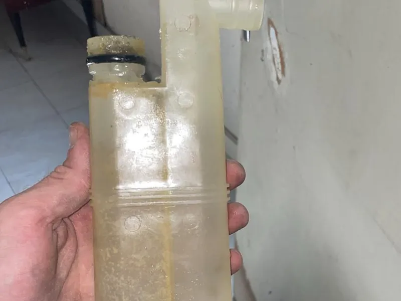 Siphon démonté et entartré tenu à la main pendant une intervention