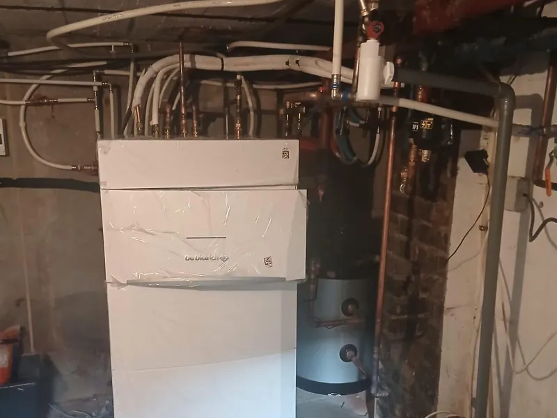 Chaudière murale et ballon d'eau chaude installés dans une chaufferie